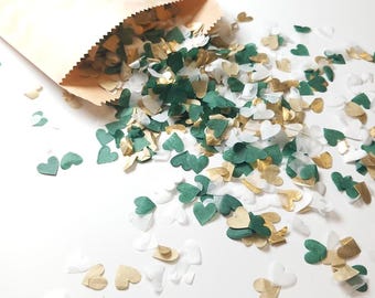 May include: A brown paper bag with green, gold, and white heart-shaped confetti spilling out. The confetti is made of paper and is perfect for a wedding or party.