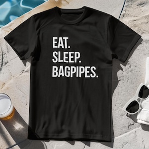 Può includere: Maglietta nera con testo bianco che dice "Eat. Sleep. Bagpipes."
