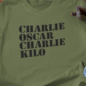 May include: A green t-shirt with the text "CHARLIE OSCAR CHARLIE KILO" printed in black.