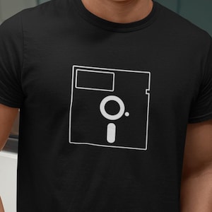May include: A black t-shirt with a white outline of a floppy disk.