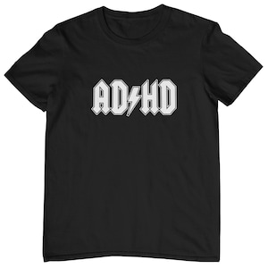 Peut inclure: T-shirt noir avec un graphique blanc du mot "ADHD" dans une police de style rock avec un éclair.