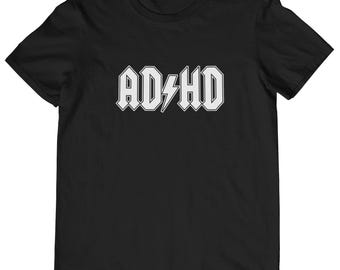 Peut inclure: T-shirt noir avec un graphique blanc du mot "ADHD" dans une police de style rock avec un éclair.