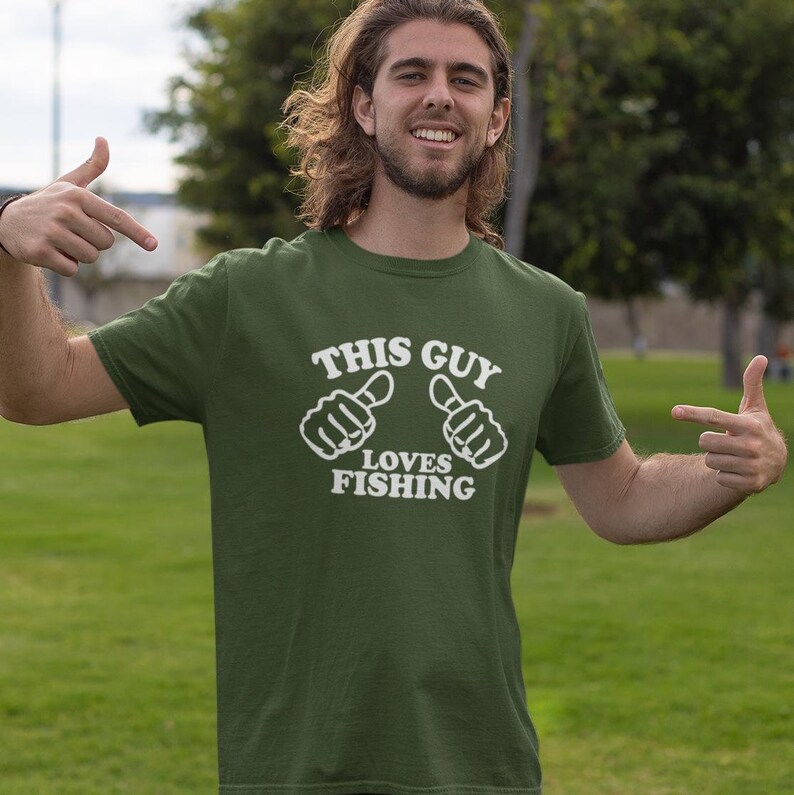 May include: A green t-shirt with white text that says "This Guy Loves Fishing" and two thumbs up symbols.