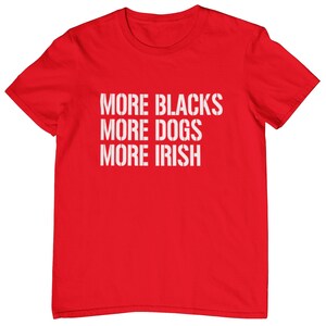 May include: Red t-shirt with the text "More Blacks More Dogs More Irish" printed in white.
