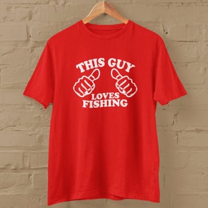 May include: Red t-shirt with white text that says "This Guy Loves Fishing" and two white thumbs up.