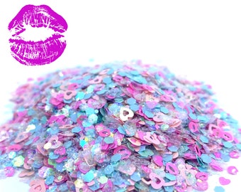 Puede incluir: Un montón de purpurina iridiscente en tonos rosa, azul y blanco. La purpurina tiene forma de corazones y hexágonos.