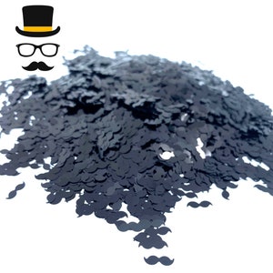 May include: A pile of black glitter shaped like mustaches.