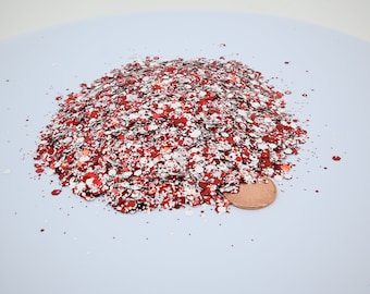 May include: A pile of red and white glitter, with a penny for scale.
