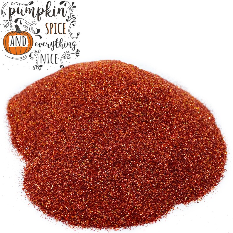 Może przedstawiać: Zbliżenie na stos pomarańczowego brokatu. Brokat jest drobny i błyszczący. Tekst "pumpkin spice and everything nice" jest napisany czarnym kursywą nad brokatem.