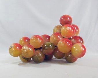 May include: A cluster of hand-carved alabaster grapes. The grapes are a mix of yellow and red, with a glossy finish.