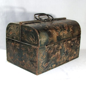 May include: A vintage, dark green metal box with an ornate floral design. The box has a hinged lid and a metal handle.
