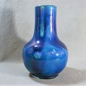 May include: A blue and purple iridescent ceramic vase with a round body and a narrow neck.