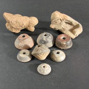May include: A collection of eight small, hand-crafted clay figurines. The figurines are in various shapes, including a bird, a human figure, and several round and square shapes. The figurines are all brown and have a rough, textured surface.