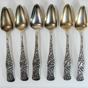May include: Set of six silver spoons with ornate handles. The spoons have a rounded, slightly pointed shape and are ideal for serving desserts or ice cream.