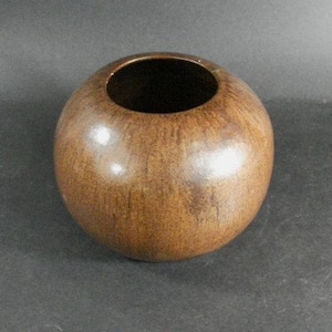 May include: A round, brown ceramic vase with a smooth, glossy finish.