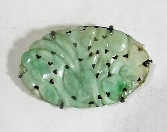 May include: A green jade pendant with a carved floral design and silver accents.