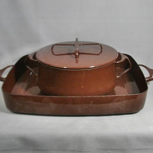 May include: A brown enameled cast iron set consisting of a square roasting pan with side handles and a matching round lidded casserole pot. The pot features a distinctive cross-shaped handle on the lid and two side handles for easy lifting.