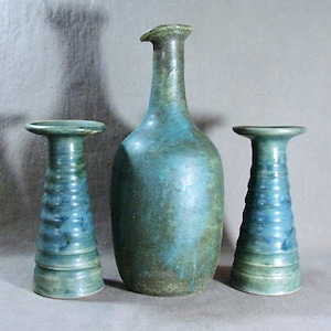 May include: Three ceramic vases in shades of blue and green. The tallest vase is a bottle shape with a narrow neck. The two smaller vases are cylindrical with a flared top.