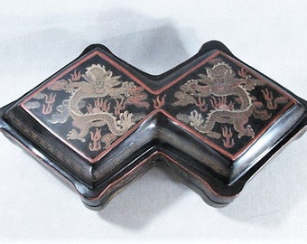May include: A black lacquered wooden box with two hinged sections. Each section features a gold and red dragon design with intricate details.