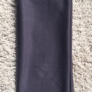 May include: A dark gray pair of leggings folded in half on a white fluffy surface.
