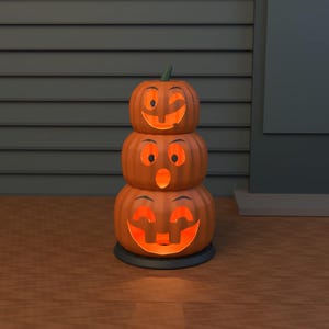 May include: A stack of three orange jack-o'-lanterns with carved faces, illuminated from within by a warm glow. The top pumpkin winks, the middle one has an open-mouthed expression, and the bottom one features a wide, toothy grin.