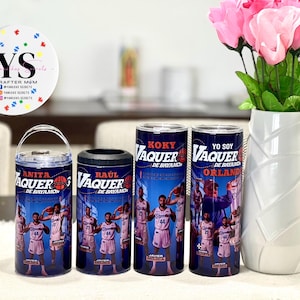 May include: A collection of blue tumblers and a can cooler featuring basketball players and the text "VAQUER" and "DE BAYAMON". A white vase with pink flowers is on the right. A sticker with the text "YS CRAFTER MOM" is on the left.
