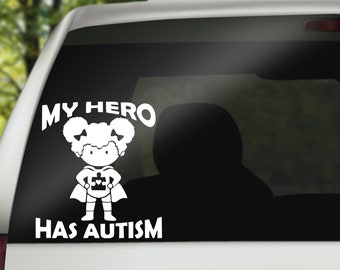 May include: White vinyl sticker with a cartoon image of a girl with curly hair wearing a superhero cape and holding a puzzle piece. The text "My Hero Has Autism" is below the image.