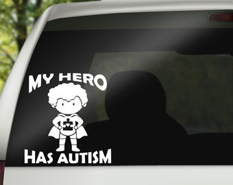 May include: White vinyl sticker with a cartoon image of a superhero child with a puzzle piece on their chest. The text "MY HERO HAS AUTISM" is written in a bold font.