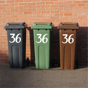May include: Three wheelie bins with the number 36 printed on the side. The bins are black, green, and brown.