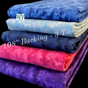 May include: Stack of five fabric squares in different shades of blue, pink, and purple. The fabric has a tie-dye pattern. The text "108" Backing - 3 Yds" is visible on the fabric.