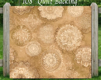 May include: A tan fabric quilt backing featuring a repeating pattern of circular mandala-style floral designs in darker brown outlines. The text 3 Yards 108" Quilt Backing is printed at the top, and a small WV logo is in the bottom right corner.