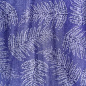 May include: A fabric textile featuring a repeating pattern of white fern leaves printed on a solid purple background. The material displays a visible woven texture throughout, with the botanical leaf shapes oriented in various directions across the surface.