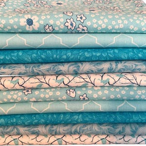 May include: A stack of 10 fabric squares in various shades of blue and white with floral, geometric, and bird patterns.