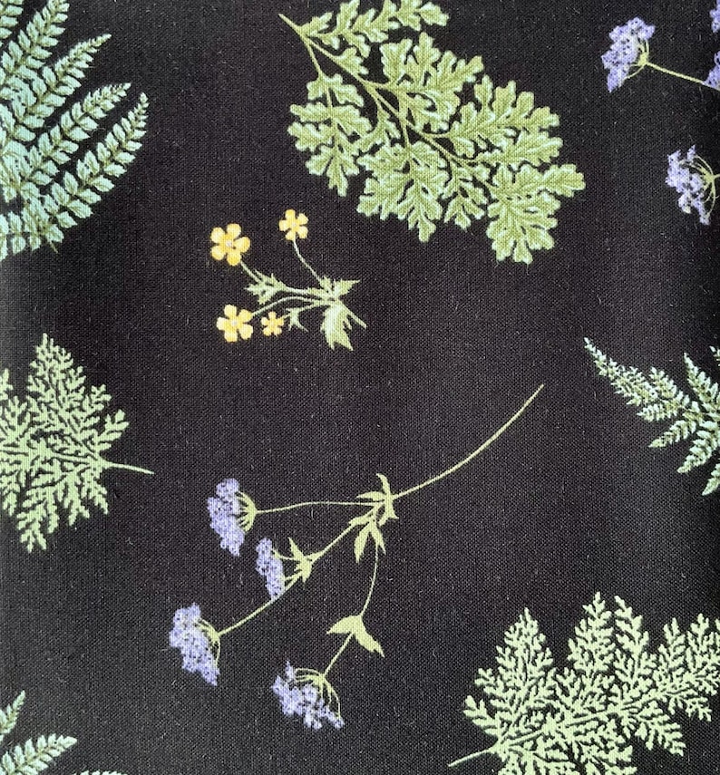 May include: A black fabric featuring a botanical print of light green fern fronds, small yellow flowers, and clusters of light purple blossoms. The pattern is distributed across the dark background, showcasing detailed leaf textures and floral stems.