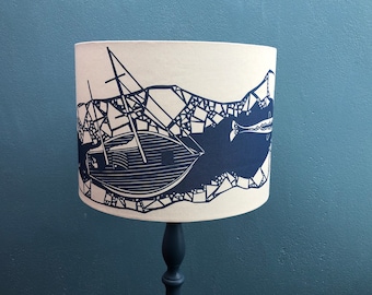 Lampshade with a wrap around design of a boat in the ice.