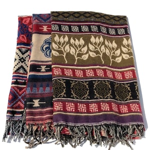 May include: Three patterned scarves with fringed edges. The scarves display diverse designs, such as geometric shapes, floral patterns, and tribal motifs. Colours include red, blue, beige, green, and purple.