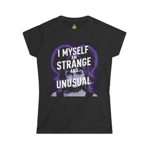 Peut inclure: T-shirt noir avec le texte "I MYSELF AM STRANGE AND UNUSUAL" en blanc. Le graphisme présente une illustration stylisée d'une personne aux cheveux violets et un ras du cou noir.