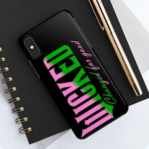 Puede incluir: Funda de teléfono negra con la palabra "WICKED" en letras grandes verdes y rosas. La frase "Changed for good" está escrita en cursiva. También se ve un bolígrafo dorado.