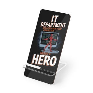 May include: A black phone stand with a Deadpool graphic. The graphic features Deadpool standing in front of a computer screen with the text "IT Department because even your computer... needs a hero".