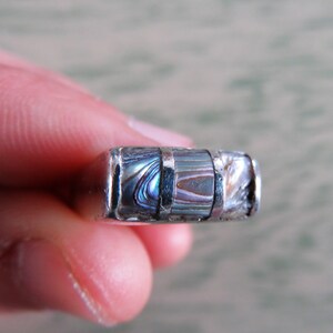 May include: A silver ring with three bands of iridescent abalone shell inlay.