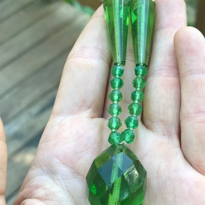 Op de afbeelding: Een groene glazen kralenketting met een grote gefacetteerde hanger en twee traanvormige kralen aan de bovenkant.