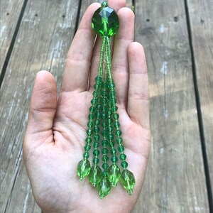 Op de afbeelding: Een groene kristallen kwast met een gefacetteerde groene kristallen top.