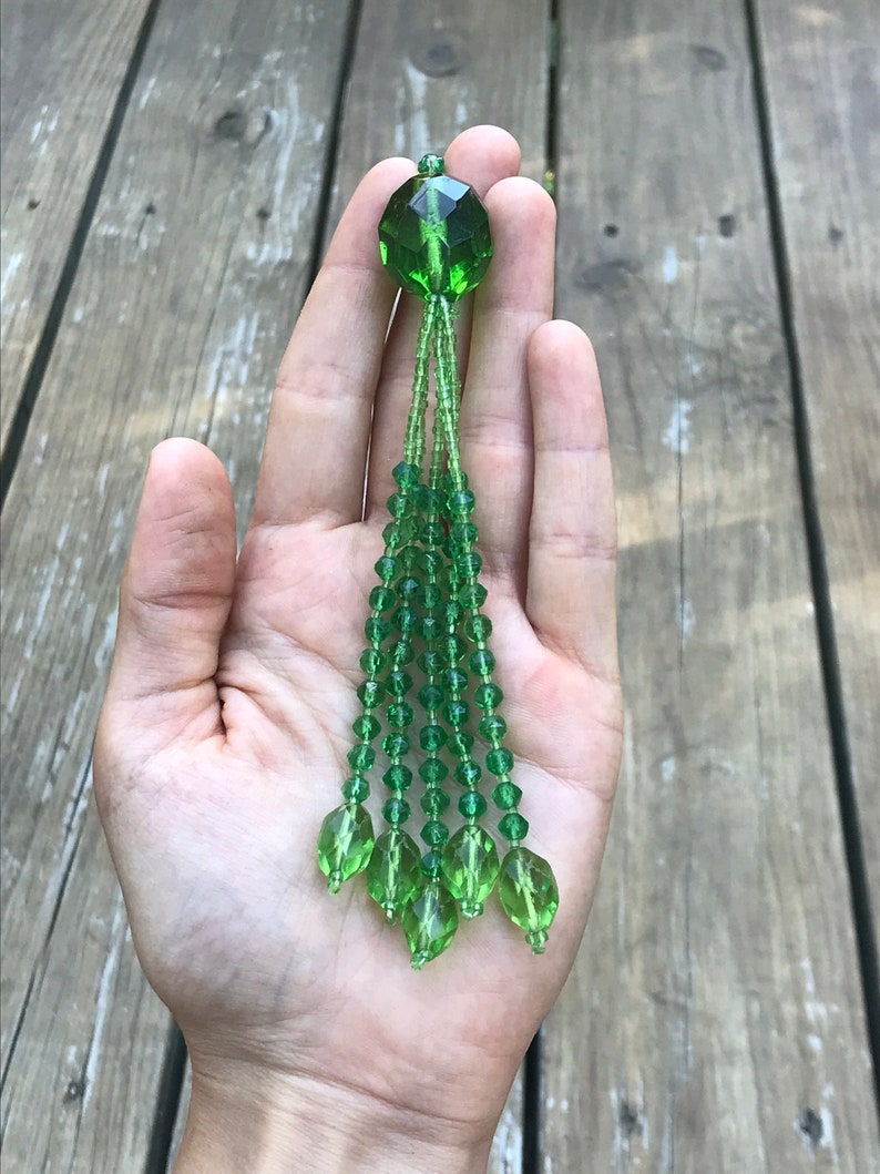Op de afbeelding: Een groene kristallen kwast met een gefacetteerde groene kristallen top.