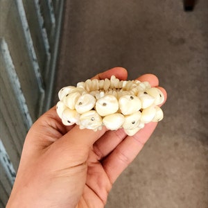 May include: A white pearl bracelet with silver accents. The bracelet is made of many small, round pearls that are strung together on a thin silver chain.