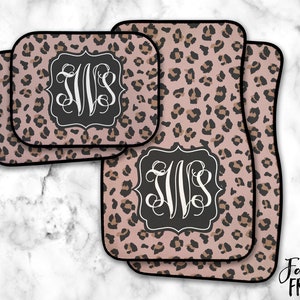May include: Three pink and brown leopard print car floor mats with black trim and a monogram in a black frame. The monogram is the letters "JVS" in white.