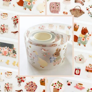 May include: Decorative washi tape roll featuring a whimsical design with a duck, bunny, and bird illustrations. The tape has a light background with floral and tea cup accents. Other stickers with similar designs are also visible.