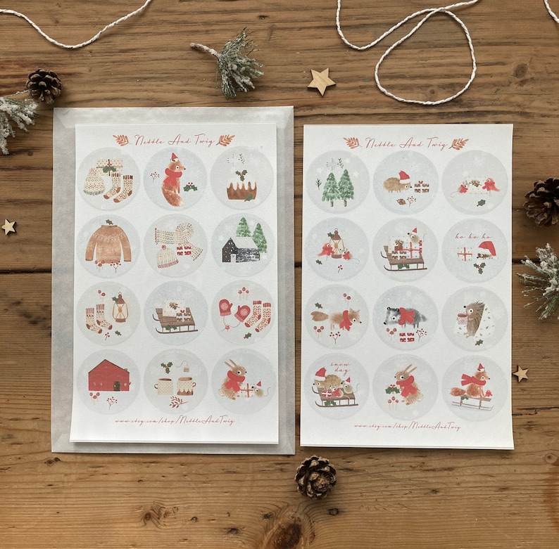 May include: Two sheets of stickers featuring a winter theme with illustrations of animals, plants, and holiday objects. The stickers are round and have a white background with a red border. The text "Nettle And Twig" appears at the top of each sheet.