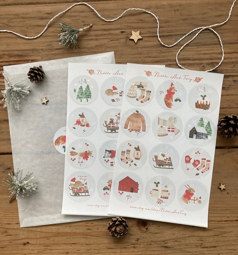 May include: Two sheets of stickers featuring illustrations of woodland animals and winter scenes. The stickers are round and have a white background with a light gray border. The text "Nibble And Twig" is printed on the top of the sheets.