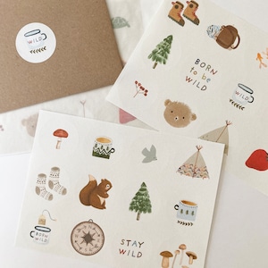 May include: A set of 10 illustrated stickers featuring woodland creatures, camping gear, and nature-inspired designs. The stickers include a squirrel, a bear, a bird, a compass, a mug, a tent, a mushroom, a tree, and a mug with the text "Born to be Wild".