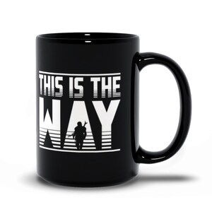 Puede incluir: Taza de caf&eacute; de cer&aacute;mica negra con un gr&aacute;fico blanco que dice "This is the Way" con una silueta de una persona sosteniendo un arma frente a un fondo a rayas.